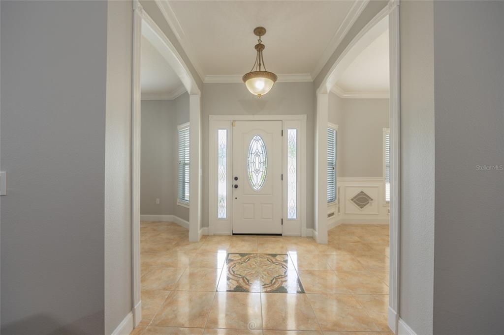 An entryway features a white front door with sidelights, tile flooring, and a hanging pendant light — 15 ROYAL PALM LANE, PALM COAST, FL