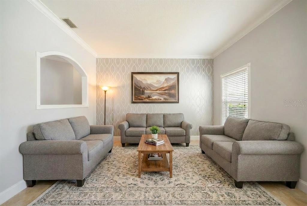 A living room features three gray sofas, a wooden coffee table, and patterned wallpaper — 15 ROYAL PALM LANE, PALM COAST, FL
