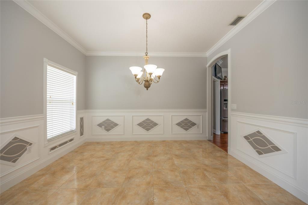 A dining room features light gray walls, white wainscoting with decorative insets, and tile flooring — 15 ROYAL PALM LANE, PALM COAST, FL
