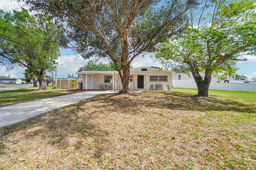 A single-story house with a carport and large trees in the front yard — 541 FIREFLY LANE, APOLLO BEACH, FL
