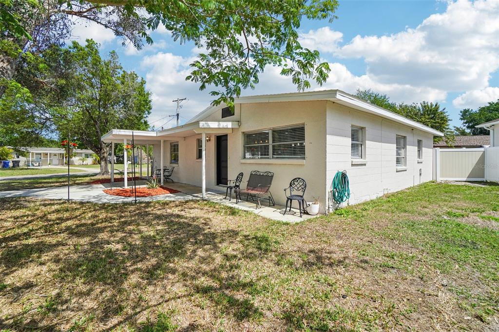 A single-story white concrete block house with a covered patio and metal outdoor furniture — 541 FIREFLY LANE, APOLLO BEACH, FL