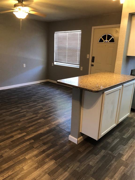 A kitchen island with a granite countertop sits in a room with wood-look flooring — 9030 BLIND PASS ROAD UNIT C10, ST PETERSBURG, FL