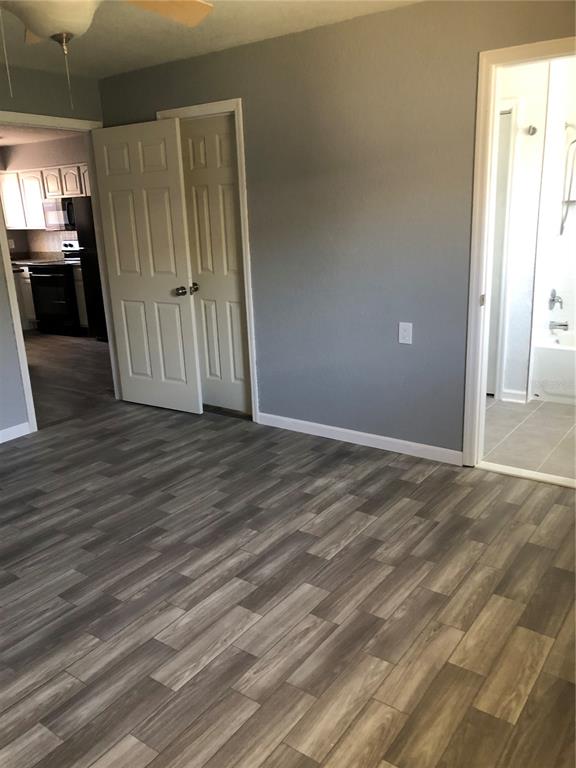 A room with gray walls, wood-look flooring, a closet, and a doorway leading to a bathroom — 9030 BLIND PASS ROAD UNIT C10, ST PETERSBURG, FL