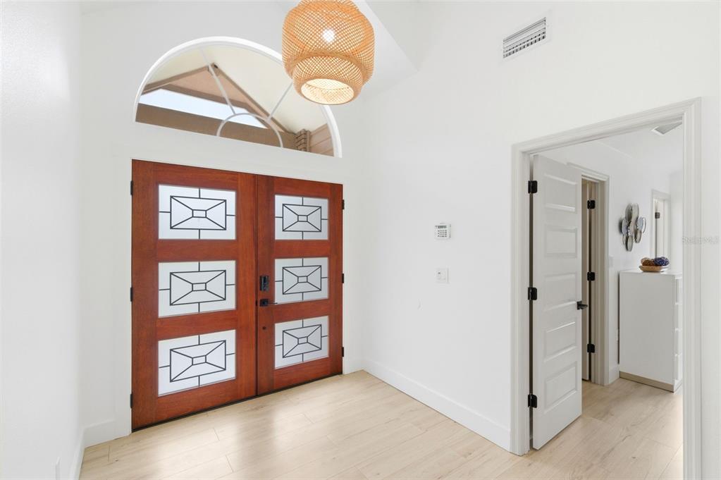 An entryway features double wood doors with geometric glass panels, light flooring, and a pendant light — 4401 LITTLE JOHN TRAIL, SARASOTA, FL