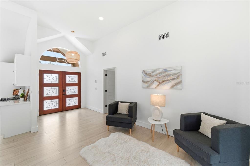 A bright living area features light wood floors, white walls, and a double front door — 4401 LITTLE JOHN TRAIL, SARASOTA, FL