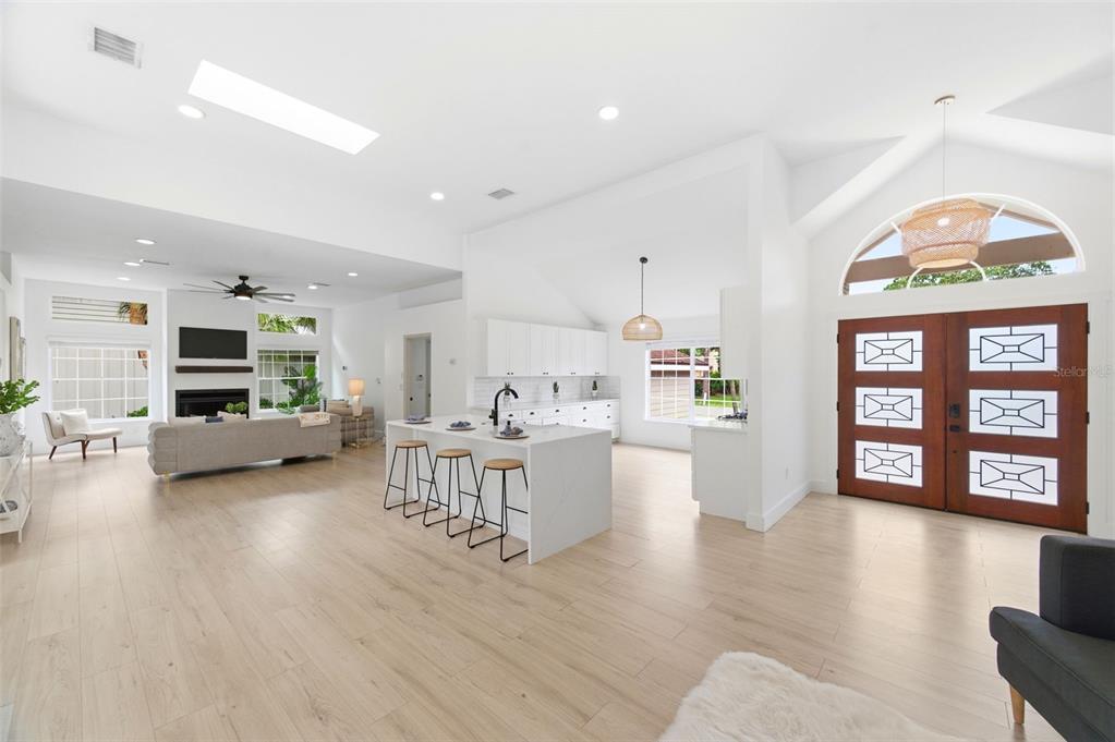 An open-concept living area features a white kitchen island, light wood flooring, and double entry doors — 4401 LITTLE JOHN TRAIL, SARASOTA, FL