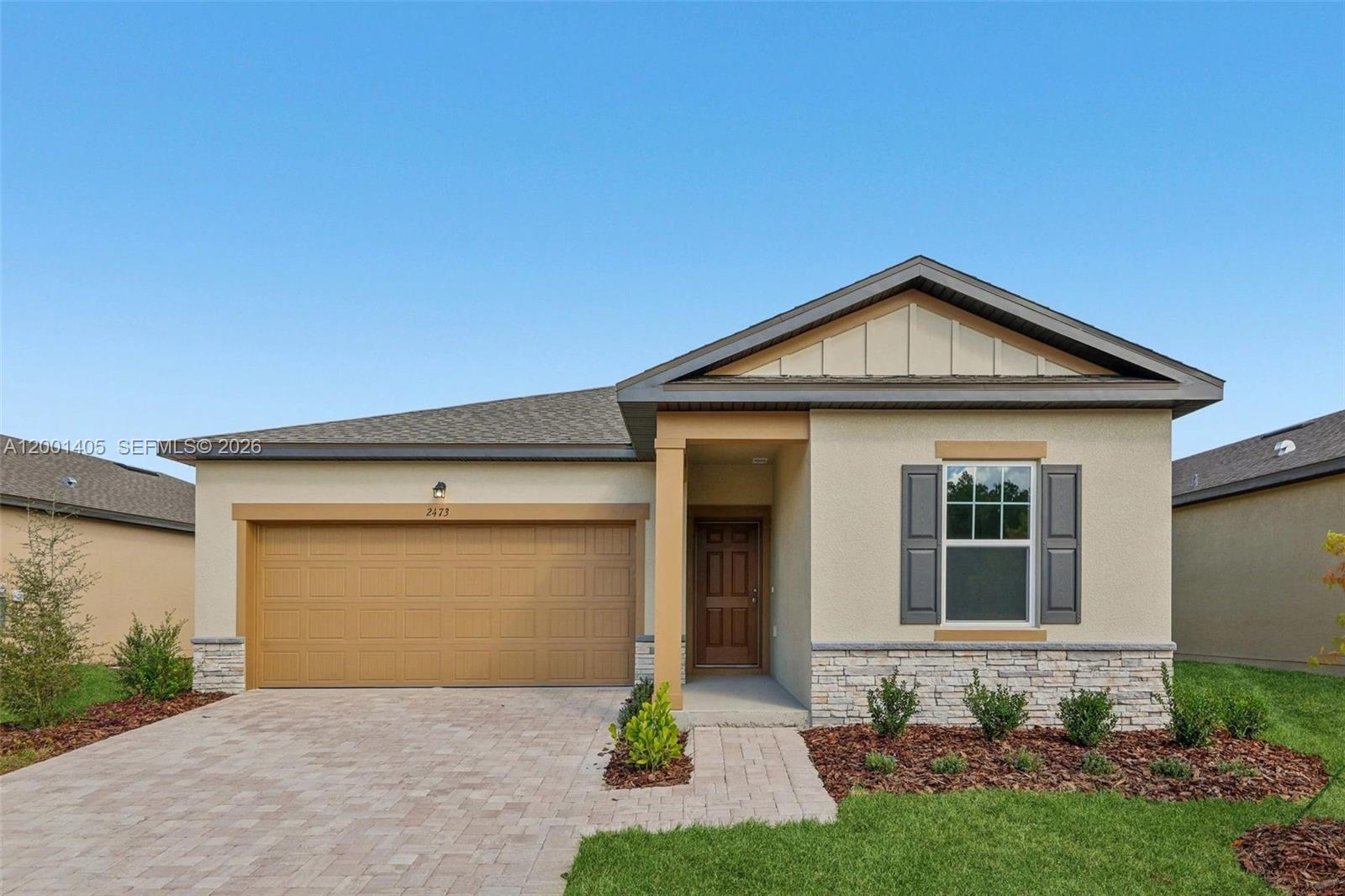 A single-story house features a tan stucco exterior, a two-car garage, and a stone facade — KISSIMMEE, FL