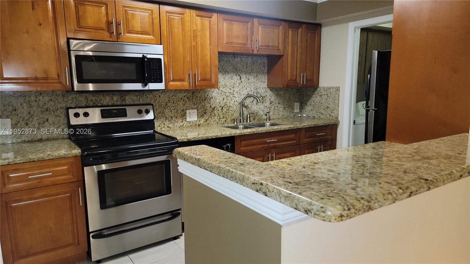 A kitchen features wood cabinets, granite countertops, and stainless steel appliances — 8401 SW 107th Ave # 234E, Miami FL 33173, MIAMI, FL