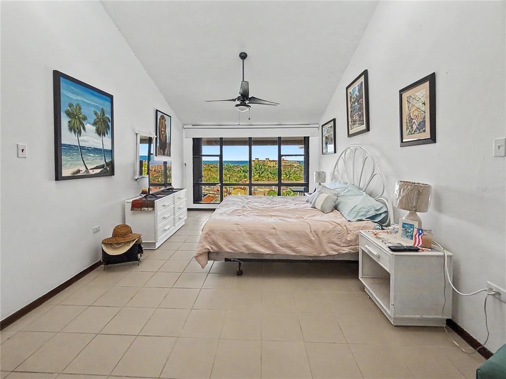 A bedroom with tile flooring, a white metal bed frame, and a large window view — 170 Palmas Dr, Humaca 170 PALMAS DR UNIT B7, HUMACAO, PR