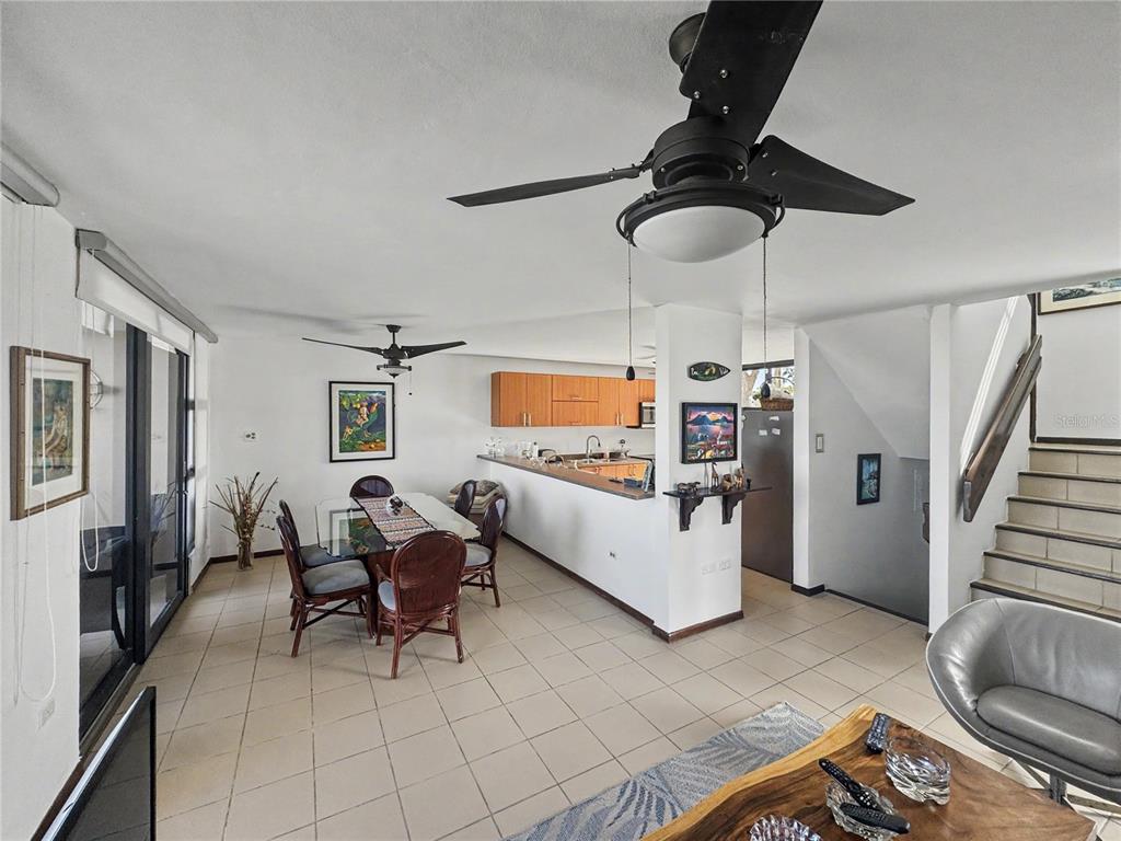 An open-concept living and dining area features tile flooring, a kitchen, and a staircase — 170 Palmas Dr, Humaca 170 PALMAS DR UNIT B7, HUMACAO, PR