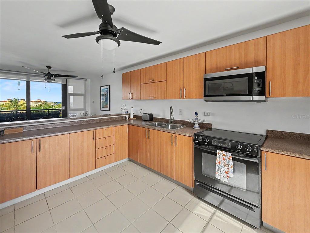 A kitchen features light wood cabinets, stainless steel appliances, and a view of the outdoors — 170 Palmas Dr, Humaca 170 PALMAS DR UNIT B7, HUMACAO, PR