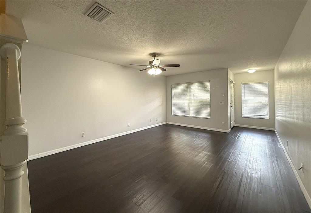An empty living room features dark wood-look flooring, light gray walls, and a ceiling fan — 254 CASTLEKEEPER PLACE, VALRICO, FL