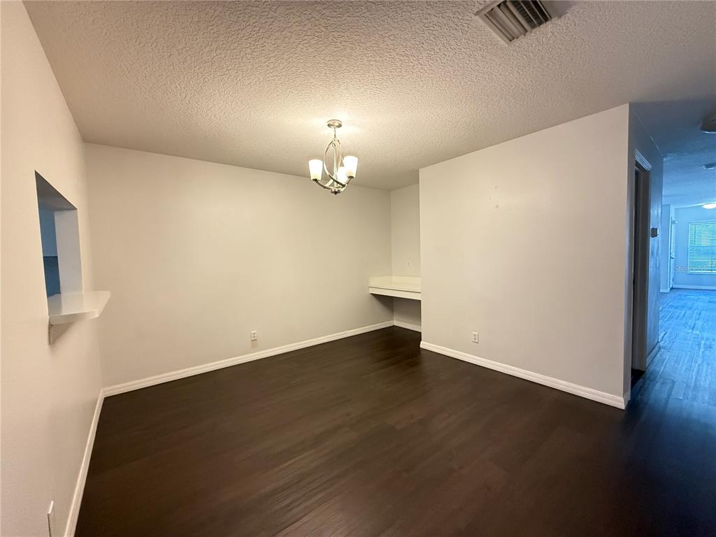 A dining area features dark wood-look flooring, a chandelier, and a built-in desk nook — 254 CASTLEKEEPER PLACE, VALRICO, FL