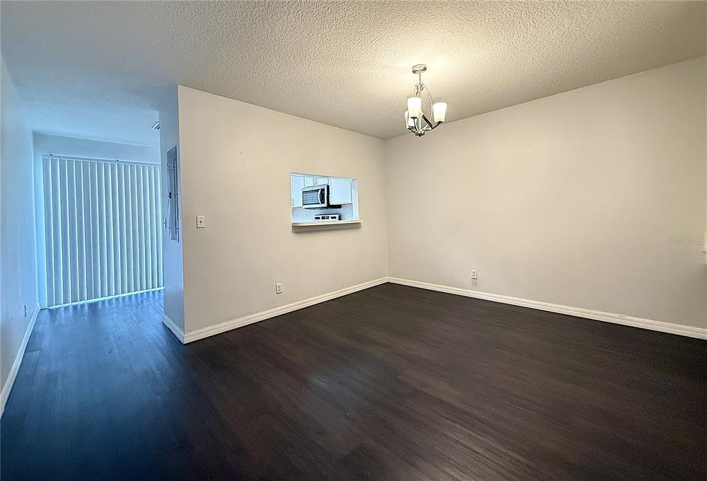 A dining area with dark wood-look flooring, white walls, and a pass-through to the kitchen — 254 CASTLEKEEPER PLACE, VALRICO, FL