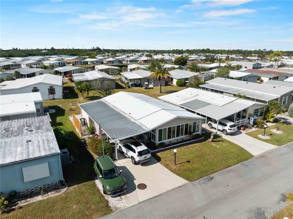A single-story manufactured home with a carport, a large front window, and a grassy lawn — 154 RAROTONGA ROAD, NORTH PORT, FL