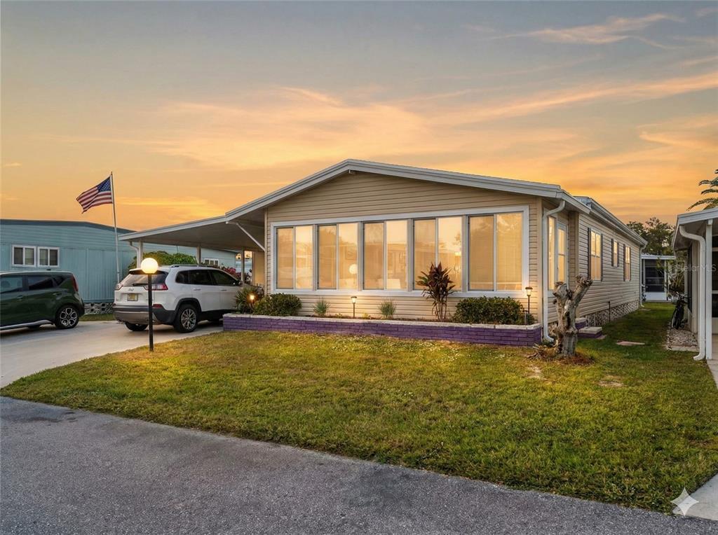 An aerial view shows a single-story house with a carport and driveway in a neighborhood — 154 RAROTONGA ROAD, NORTH PORT, FL