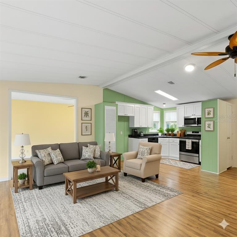 A living room features a green accent wall, gray sofa, two patterned chairs, and wood flooring — 154 RAROTONGA ROAD, NORTH PORT, FL