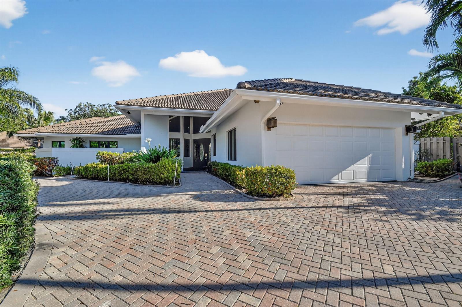 A white house with a tiled roof and a brick driveway leads to the front entrance — 2410 Embassy Drive, West Palm Beach FL 33401, WEST PALM BEACH, FL