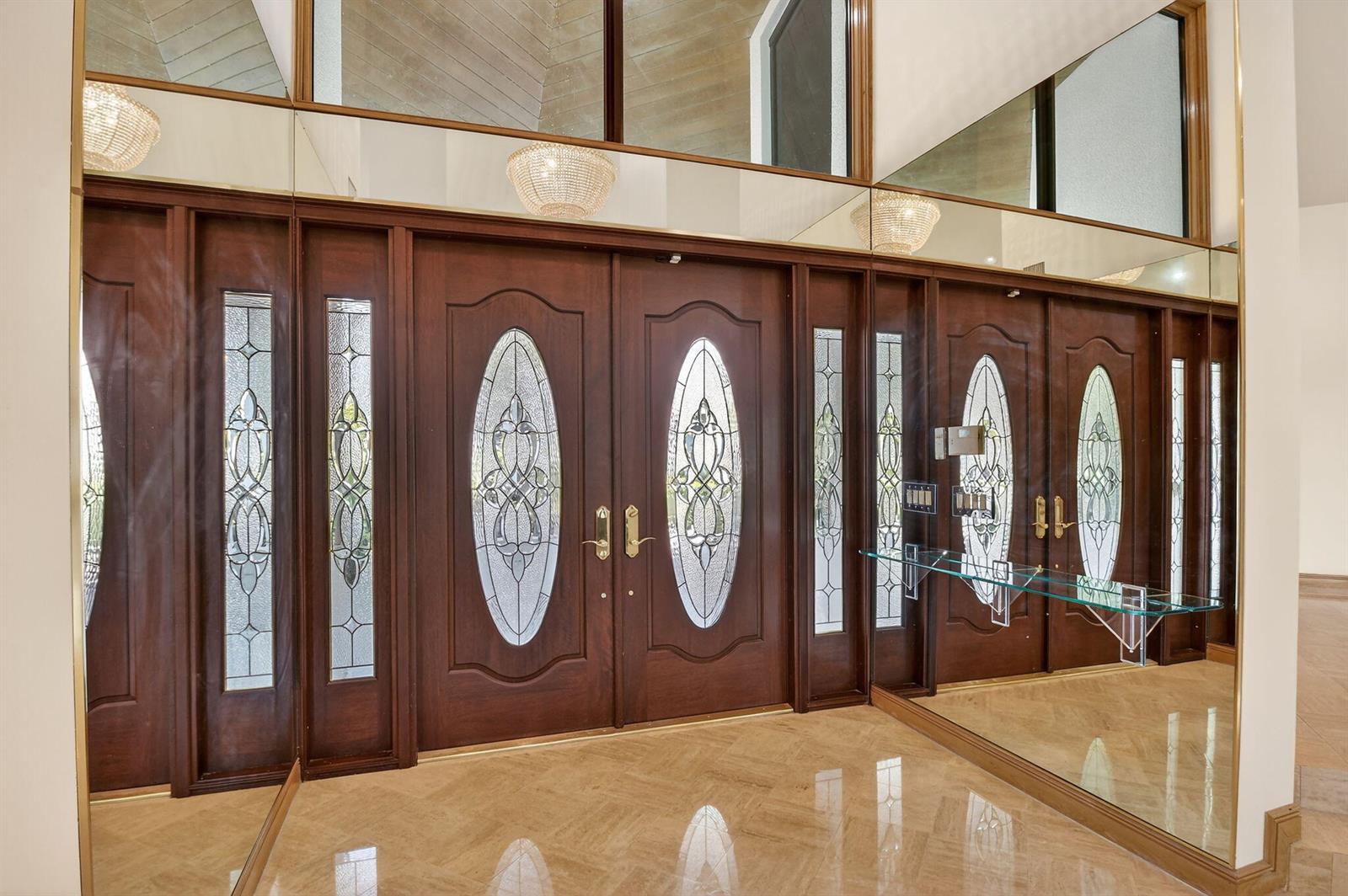 A grand entryway features double wooden doors with oval glass inserts, sidelights, and mirrored walls — 2410 Embassy Drive, West Palm Beach FL 33401, WEST PALM BEACH, FL