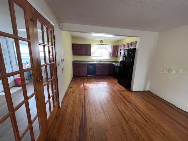 A kitchen with dark wood cabinets and hardwood floors viewed through glass-paned double doors — 356 CLIFTON AVENUE, HOLLY HILL, FL