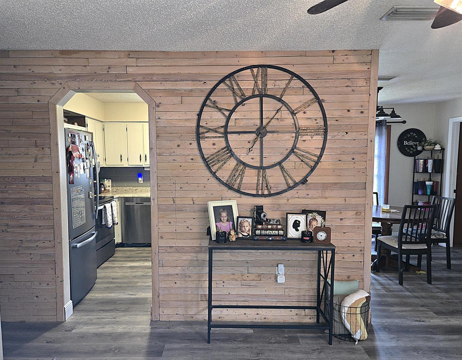 A wood-paneled accent wall features a large decorative clock above a metal console table — 211 NE 3rd Terrace, Williston FL 32696, WILLISTON, FL