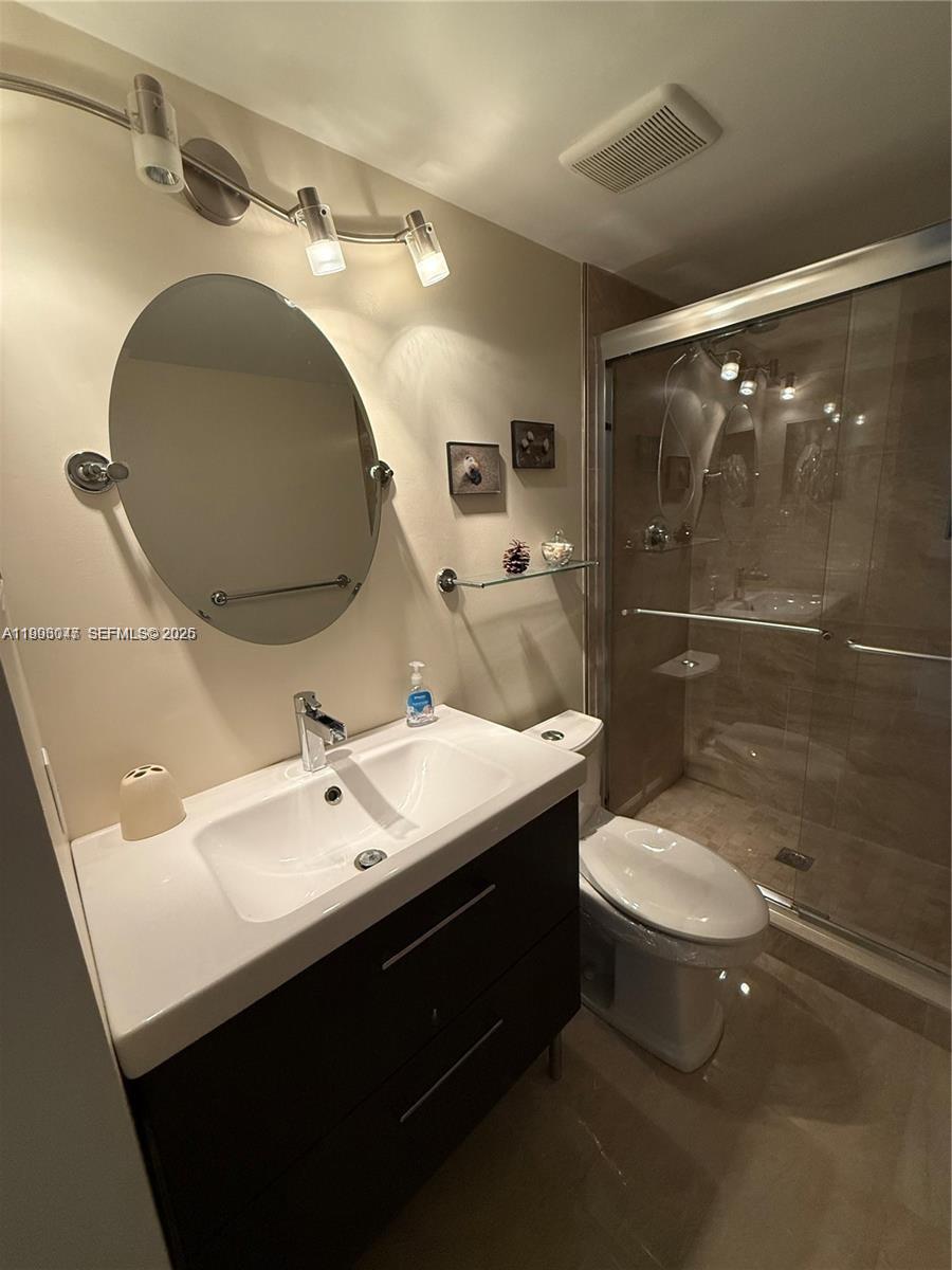 A bathroom features a vanity with a white sink, an oval mirror, and a glass-enclosed shower — 627 Waterside Dr # 627, Hypoluxo FL 33462, HYPOLUXO, FL