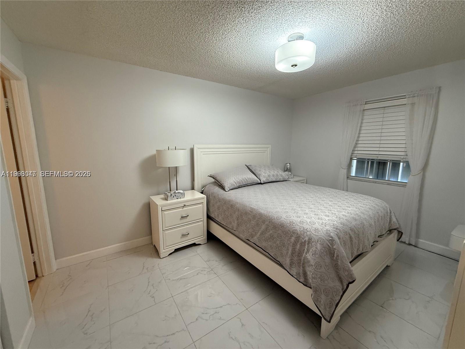 A bedroom features a white bed, a matching nightstand, and light-colored tile flooring — 627 Waterside Dr # 627, Hypoluxo FL 33462, HYPOLUXO, FL