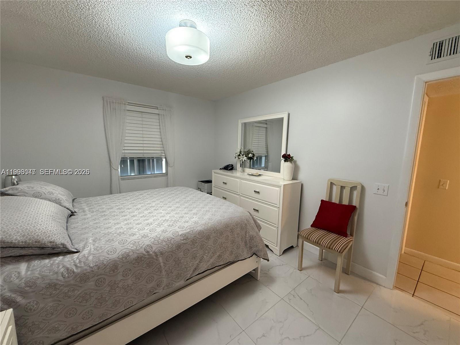 A bedroom features a bed, a white dresser with a mirror, and a wooden chair — 627 Waterside Dr # 627, Hypoluxo FL 33462, HYPOLUXO, FL
