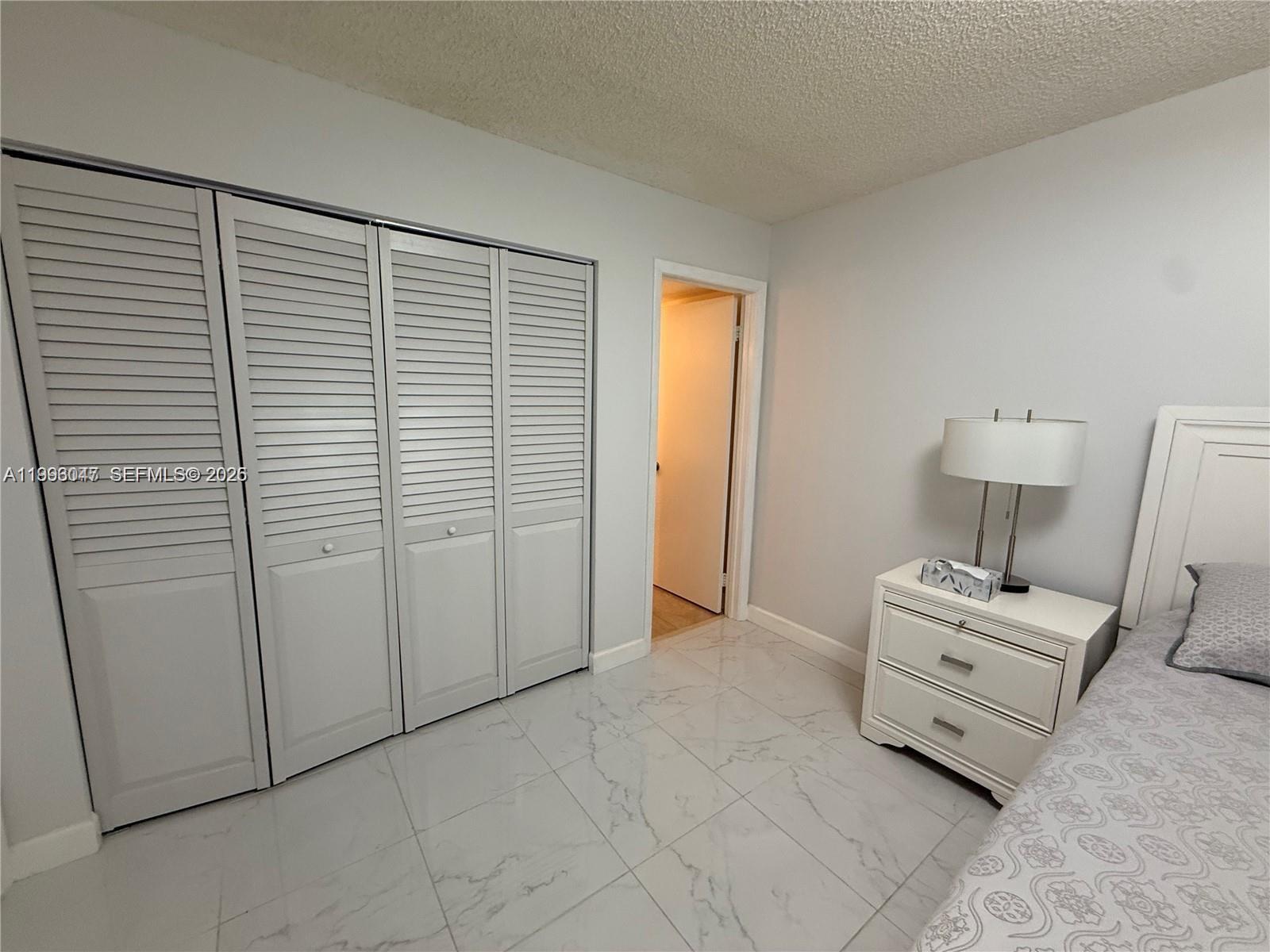 A bedroom features light gray walls, white tile flooring, a closet with louvered doors, and furniture — 627 Waterside Dr # 627, Hypoluxo FL 33462, HYPOLUXO, FL