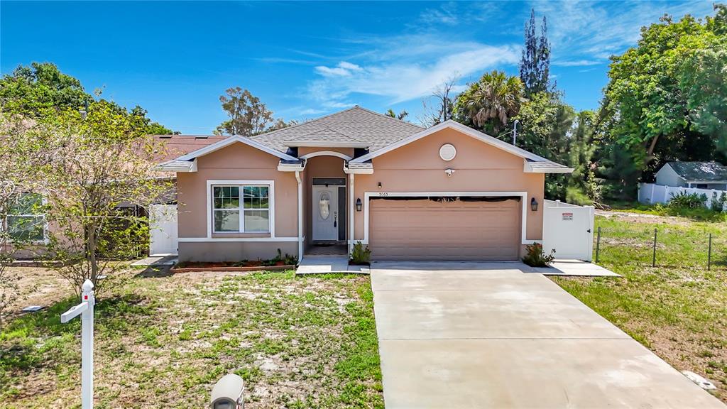 A single-story house with a tan stucco exterior, a two-car garage, and a concrete driveway — 5065 67TH WAY N, ST PETERSBURG, FL