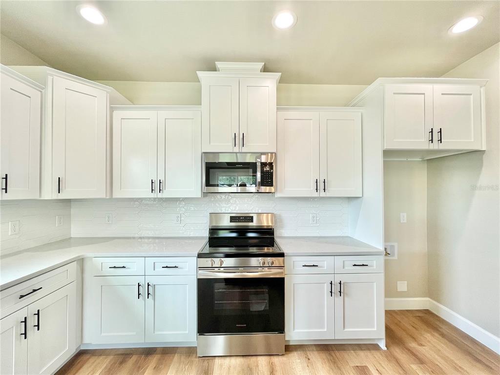 A kitchen features white shaker cabinets, stainless steel appliances, and a light-colored tile backsplash — 146 SW 212TH DRIVE, NEWBERRY, FL