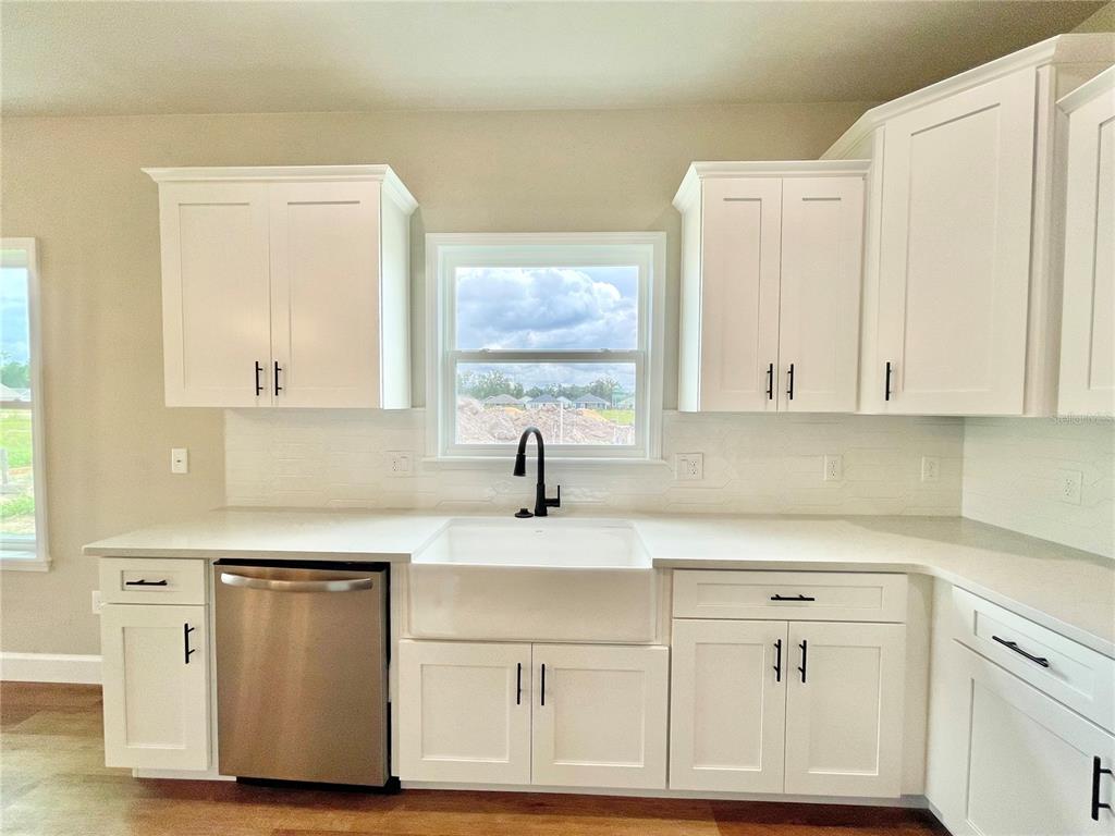 A kitchen features white cabinets, a farmhouse sink, a stainless dishwasher, and light countertops — 146 SW 212TH DRIVE, NEWBERRY, FL