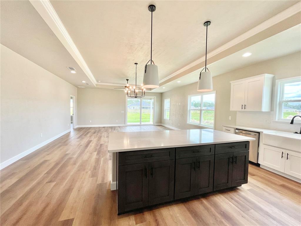 A kitchen with a dark island, white cabinets, and pendant lights opens to a living area — 146 SW 212TH DRIVE, NEWBERRY, FL