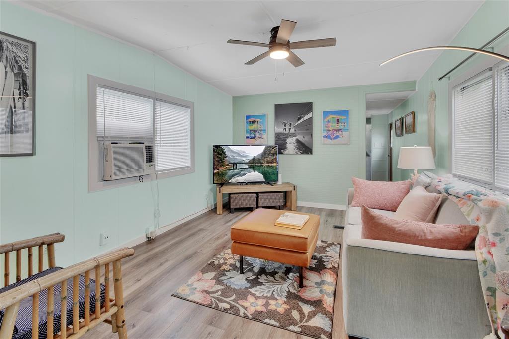 A living room with light green walls, wood-look flooring, a ceiling fan, and a sofa — 109 CYPRESS DRIVE, DEBARY, FL