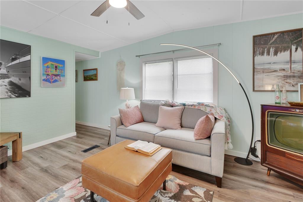 A living room features light blue walls, a grey sofa, a leather ottoman, and wood flooring — 109 CYPRESS DRIVE, DEBARY, FL