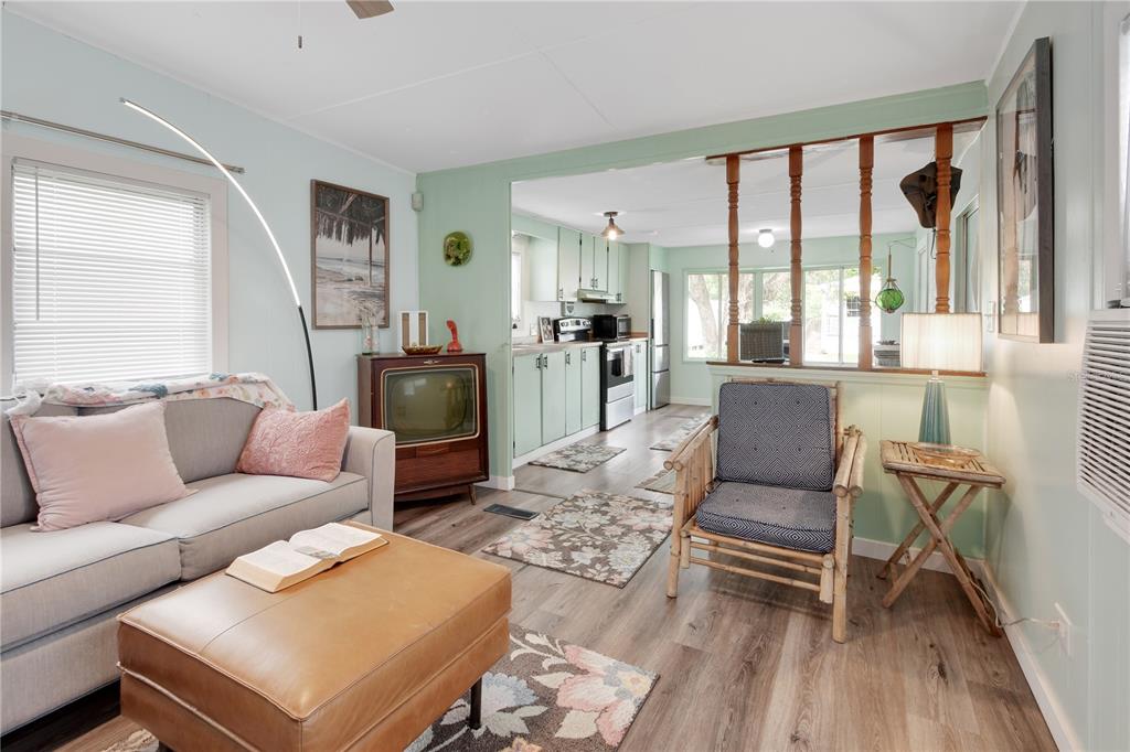A living room with light green walls, wood-look flooring, a sofa, and an open kitchen — 109 CYPRESS DRIVE, DEBARY, FL