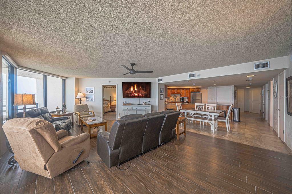 A living room with wood-look tile floors, a fireplace, and an open kitchen area — 3855 S ATLANTIC AVENUE UNIT 1004, DAYTONA BEACH, FL