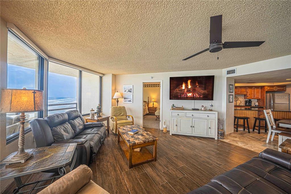 A living room with wood-look tile floors, a fireplace, and a view of the ocean — 3855 S ATLANTIC AVENUE UNIT 1004, DAYTONA BEACH, FL