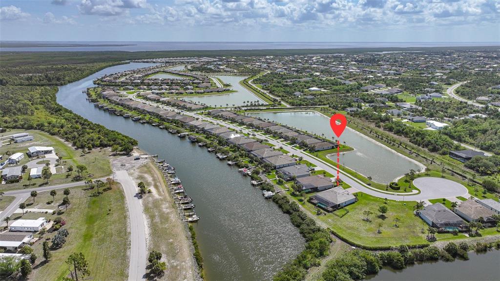 An aerial view shows a waterfront residential neighborhood with a canal, pond, and houses — 14332 PONCE DE LEON TRAIL, PORT CHARLOTTE, FL