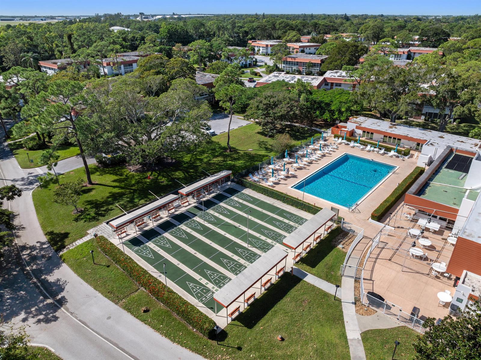 An aerial view shows a swimming pool and shuffleboard courts next to apartment buildings — 2600 SE Ocean Boulevard # N14, Stuart FL 34996, STUART, FL