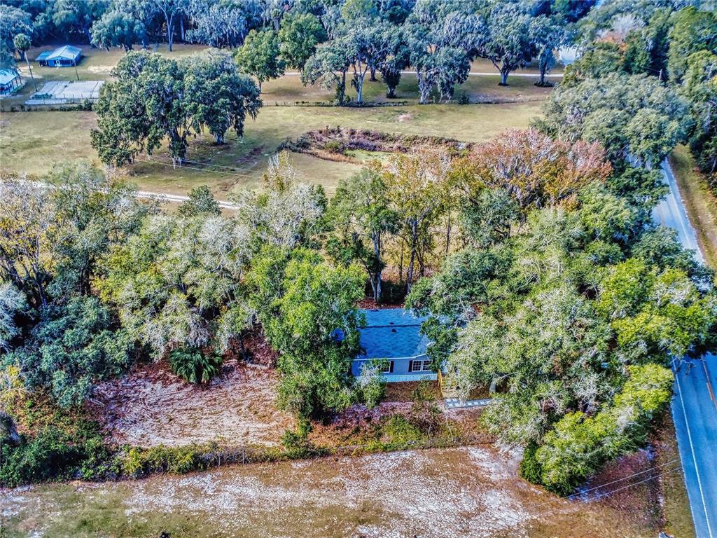 An aerial view shows a house nestled among mature trees next to a paved road — 4300 NE 175TH STREET ROAD, CITRA, FL