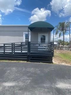 A gray mobile home features a dark wooden deck with a green arched awning — 9200 66TH STREET N, PINELLAS PARK, FL