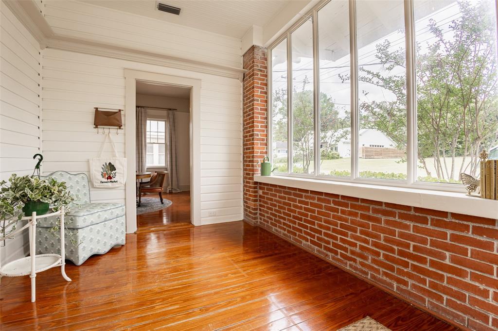 A sunroom features hardwood floors, white shiplap walls, a brick accent wall, and large windows — 825 SE SANCHEZ AVENUE, OCALA, FL