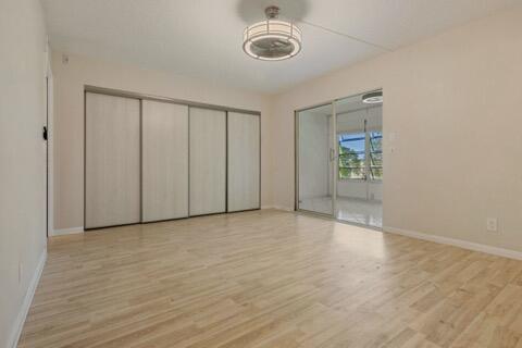 A bedroom with light wood-look flooring, a large sliding closet, and a glass patio door — 4028 Berkshire # B, Deerfield Beach FL 33442, DEERFIELD BEACH, FL