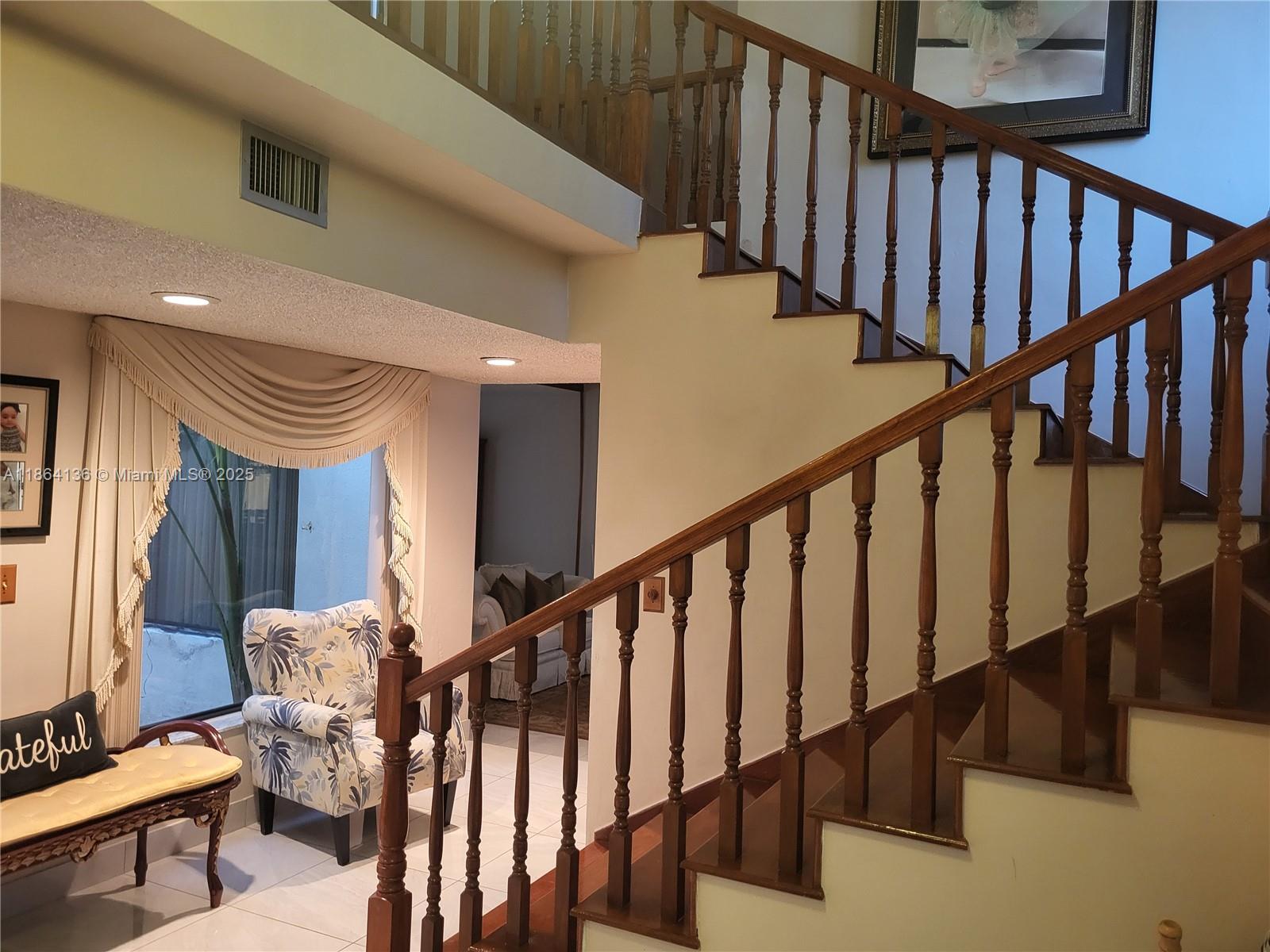 A wooden staircase with a railing leads to an upper level near a seating area — 2930 SW 129 Ave, Miami FL 33175, MIAMI, FL