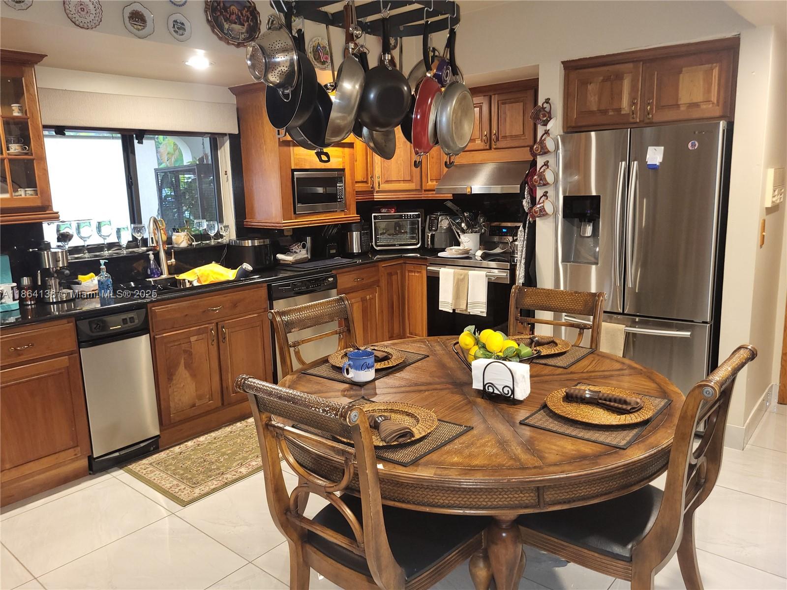 A kitchen features wood cabinets, stainless steel appliances, a hanging pot rack, and a dining table — 2930 SW 129 Ave, Miami FL 33175, MIAMI, FL