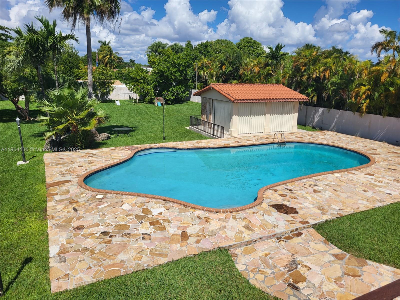 A swimming pool with a stone deck sits in a backyard with a small shed — 2930 SW 129 Ave, Miami FL 33175, MIAMI, FL