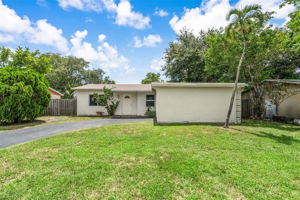 A single-story house with a beige exterior, a front door, and a paved driveway — 405 SW 77TH AVENUE, NORTH LAUDERDALE, FL