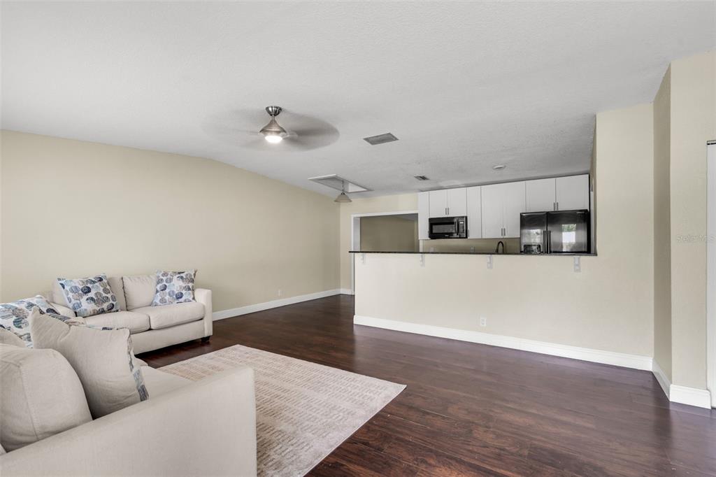 A living room with dark wood floors flows into an open kitchen with white cabinets — 405 SW 77TH AVENUE, NORTH LAUDERDALE, FL