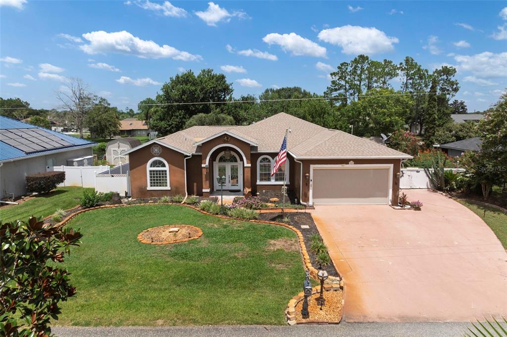 A single-story suburban house with a brown stucco exterior, a two-car garage, and a lawn — 52 BUTTONWORTH DRIVE, PALM COAST, FL